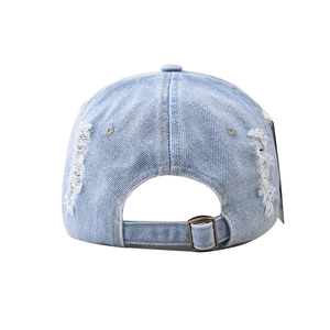 Detail view of washed blue denim baseball cap with distressed rip and metal buckle
