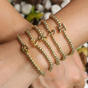 Stackable 18k gold plated beaded zodiac bracelets featuring celestial charms on a model