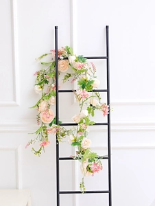 Realistic pink and champagne silk roses with green leaves draped on a black metal frame