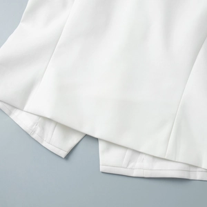 Detailed close-up of white twill vest hem featuring fine stitching and split overlap design