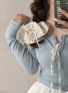 Close-up of a cream polka dot scrunchie with a ribbon tie on a braided hairstyle