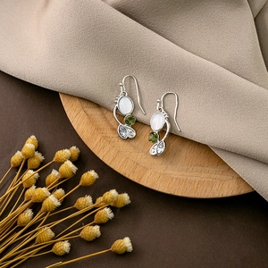 Detail of silver bohemian earrings with white oval stone and green zircon droplets