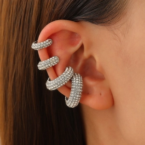 Detalle de cuatro pendientes ear cuff plateados con circonitas brillantes en la oreja