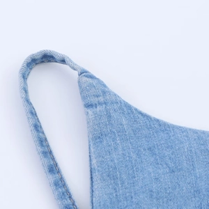 Vue macro détaillée montrant les coutures jaunes et la texture du denim bleu clair