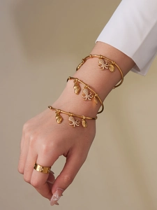 Close-up of golden ocean-themed bangles with octopus charms and a sparkling clover ring