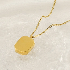 Detail showing gold rectangular pendant on cable chain with mirror-polished surface