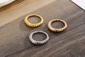 Macro shot of three croissant rings in gold, silver, and rose gold on a wooden surface