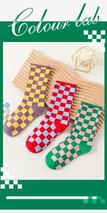 Three pairs of retro checkered crew socks in vibrant color combinations on a wooden display