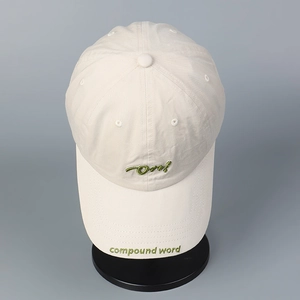 Detalle de gorra de béisbol beige con bordado verde y textura de tela de calidad