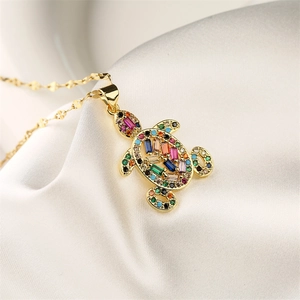Detail of a golden turtle pendant with vibrant colorful rectangular gemstones on fabric