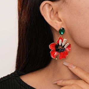 Boucles d'oreilles fleurs rouges rétro avec gemme verte portées par un mannequin