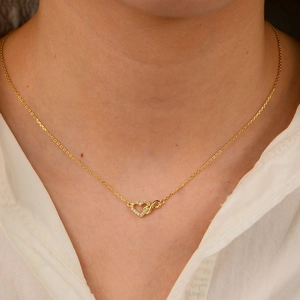 Gold infinity heart necklace for women with white crystal inlay worn by a model