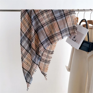 Close-up of beige, brown and blue plaid scarf with fringe detail on a metal hanger