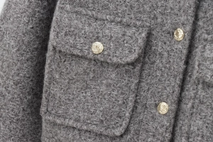 Vue macro de la texture en laine et des boutons dorés gaufrés de la veste grise