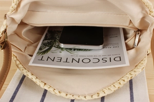 Detail showing the inner zipper pocket of the woven bag with smartphone and magazine