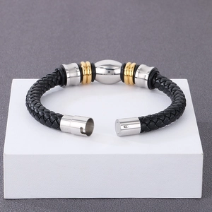 Détail d'un bracelet en cuir tressé noir avec fermoir magnétique en acier argenté et doré