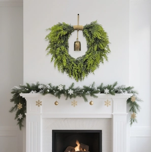 Close-up of heart-shaped cedar wreath with rustic metal bell on a cozy fireplace