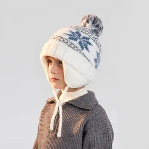 Kids winter knit hat with earflaps, white snowflake pattern and large pom pom