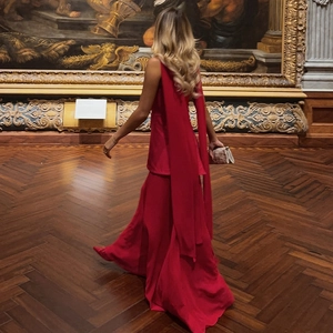 Robe de soirée rouge dos nu avec rubans et fente dans une galerie d'art classique
