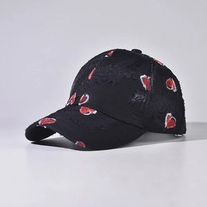 Detailed view of distressed edges and red heart patterns on a black baseball cap