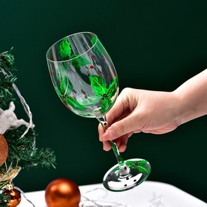 Hand-painted Christmas tree wine glass featuring holly leaves and red berries design