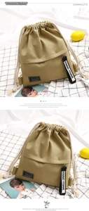 Detail of khaki drawstring canvas backpack with fashion label and monochrome ribbon strap