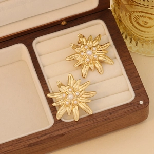 Elegant gold stainless steel flower earrings with white faux pearls on a velvet display
