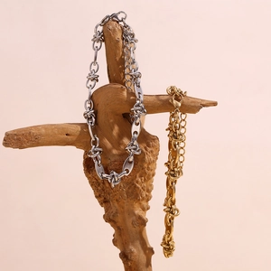 Detail showing gold and silver twisted knot coffee bean links on a natural wood stand