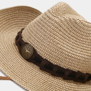 Detail of western straw cowboy hat with brown suede band and bronze star metal emblem