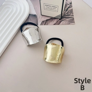 Detail of minimalist metallic hair tie with irregular hammered texture in gold and silver