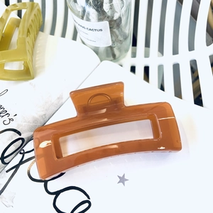 Detail of a large amber caramel rectangle hollow hair claw clip on a white shelf