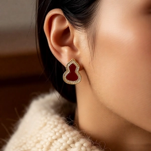 Close-up of vintage Wulu gourd earring with red agate and zircon on ear model