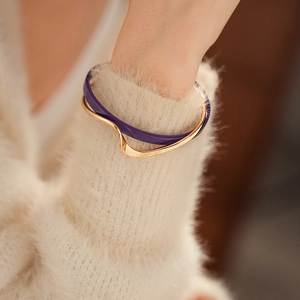 Detail of a double-layered gold-plated geometric bracelet with purple enamel on wrist