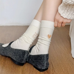 Detail of white cotton socks with heart and 'Follow your heart' embroidery at the cuff