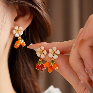 Detail of vintage-style flower and berry earrings with glossy orange pendants