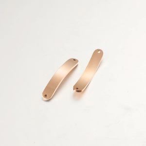 Macro shot of two curved rose gold stainless steel bar connectors with dual holes