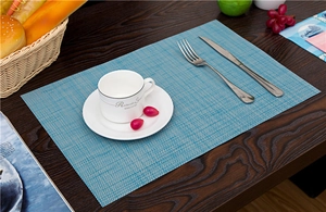 Close-up of light blue woven PVC table mat texture on dark wooden dining table