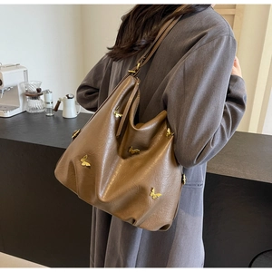 Detail view of a large brown PU leather shoulder bag with golden butterfly ornaments