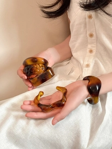 Macro shot of irregular amber acrylic resin bracelets on vintage linen fabric