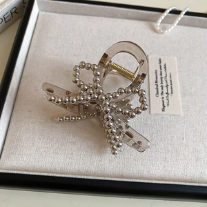 Close-up of a silver beaded bow hair claw with transparent acrylic base and metal spring