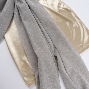 Détail macro du tissu pailleté argenté et du satin doré avec un éclat métallique