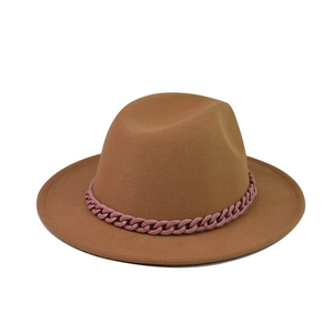 Détail d'un chapeau fedora en laine marron orné d'une chaîne décorative en plastique rose mat
