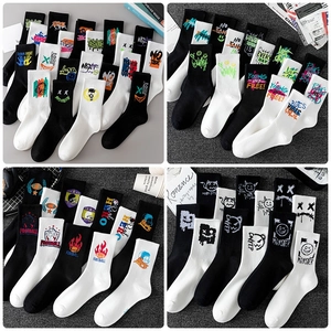 Detail view of street style mid-calf socks with graffiti and letter prints on dark surface