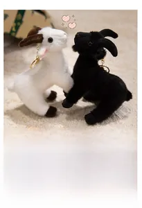 Close-up of cute black plush goat keychain with fluffy texture and gold metal ring hook
