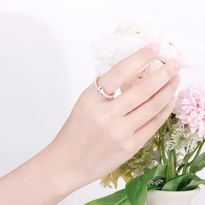 Detail of snake-shaped silver ring with white stones and green gemstone eyes on hand
