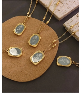 Detailed view of five 18K gold plated necklaces featuring grey rose pendants on stone