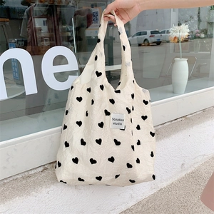 Close-up of heart pattern textured canvas tote bag with woven studio label