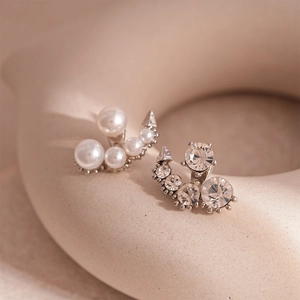Macro shot of asymmetrical silver earrings with white faux pearls and sparkling rhinestones