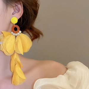 Close-up of model wearing large yellow fabric flower earrings with layered petal detail