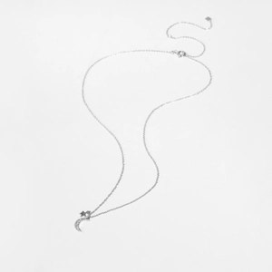 Macro shot of silver crescent moon and star pendant necklace with sparkling white zircons